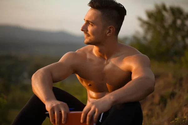 Sonriente hombre musculoso con libro al aire libre — Foto de Stock