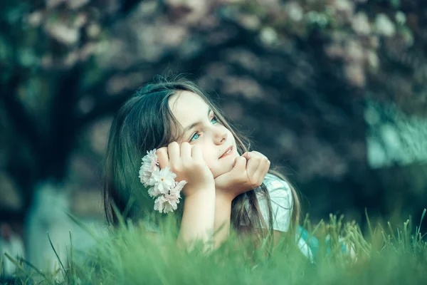 Kleines Mädchen auf blühendem Gras — Stockfoto