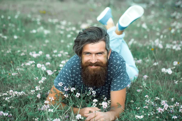 Homme barbu posé sur l'herbe verte souriant — Photo