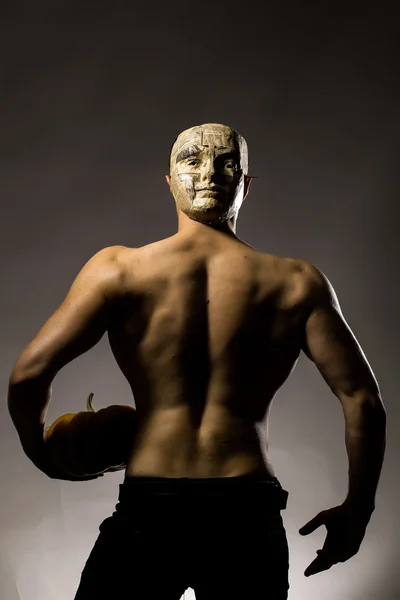 Мускулистый человек в маске с тыквой — стоковое фото