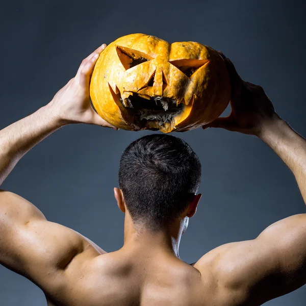 Hombre musculoso en máscara con calabaza — Foto de Stock