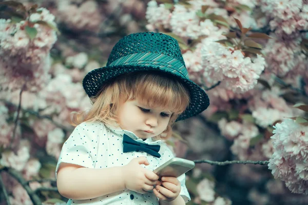 Retro boy with phone in blossom — Stock Photo, Image