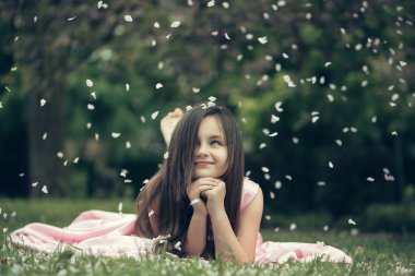 Yaprakları yeşil çimenlerin üzerinde küçük kız