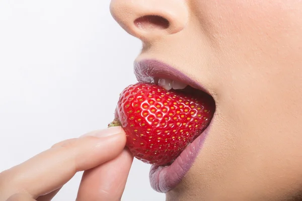 Labios femeninos comiendo fresa roja — Foto de Stock