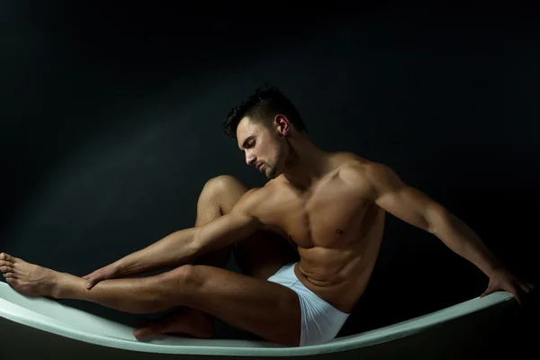 Muscular man on bathtub — Stock Photo, Image