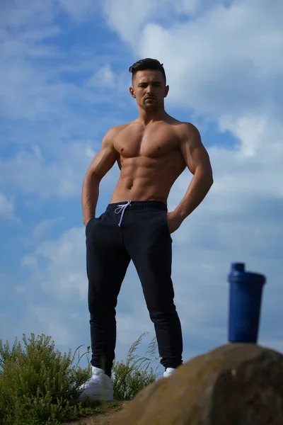 Muscular man posing near water bottle — Stock Photo, Image