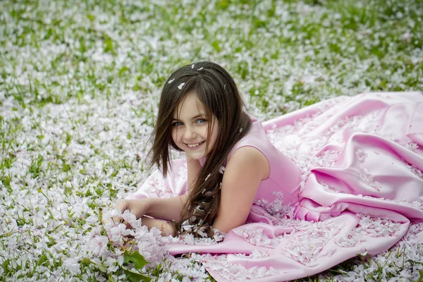 花びらと緑の草の上の少女 — ストック写真