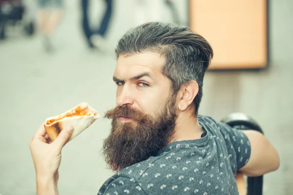 Красивый бородатый мужчина ест пиццу — стоковое фото