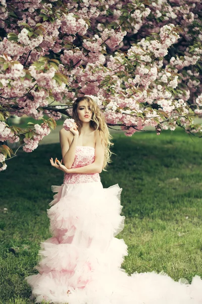 Vrouw in roze jurk in de buurt van bloom — Stockfoto