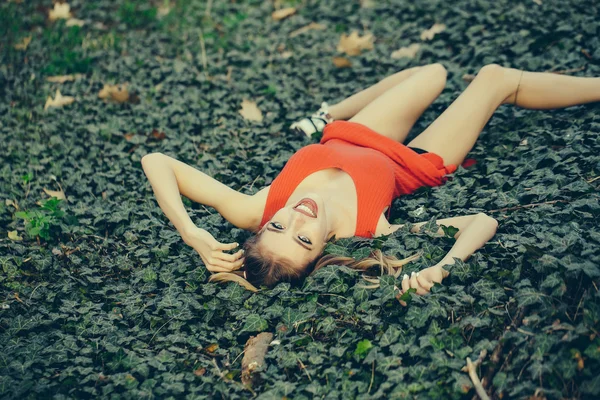 Ragazza sorridente sdraiata su foglie verdi — Foto Stock