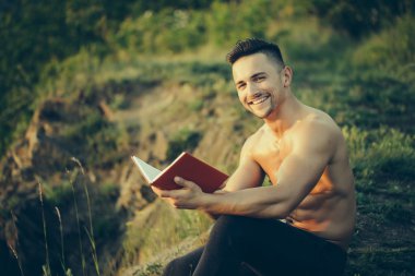 Kitap açık ile gülümseyen kaslı adam