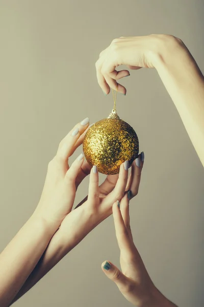 Vrouwelijke handen met gouden kerst bal — Stockfoto