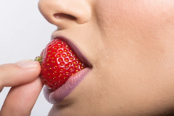 Labios femeninos comiendo fresa roja — Foto de Stock