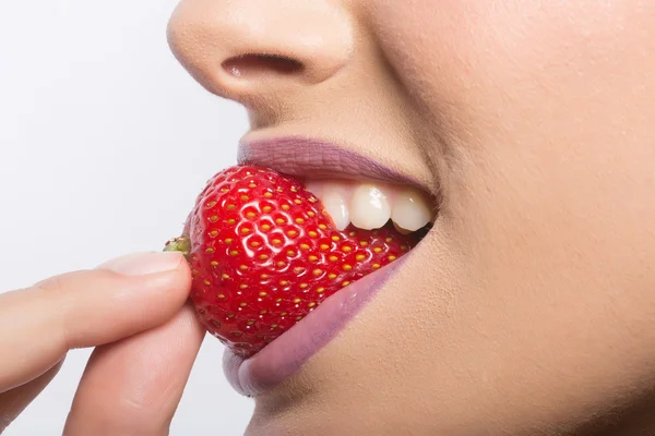 Labios femeninos comiendo fresa roja — Foto de Stock