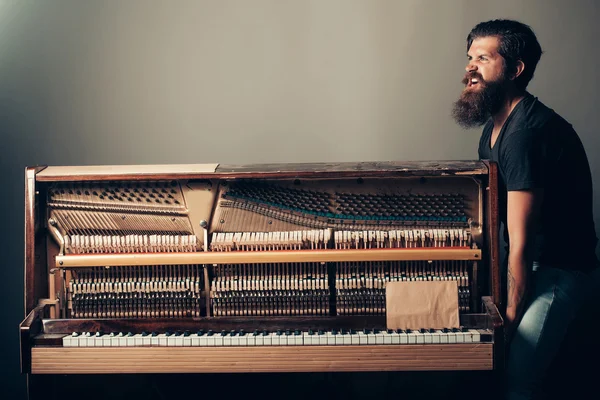 Γενειοφόρος άνδρας προσπαθεί να μετακινήσετε το ξύλινο πιάνο — Φωτογραφία Αρχείου