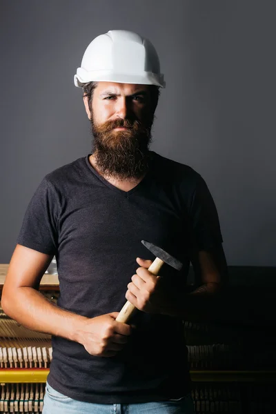 Hombre en casco cerca de piano con martillo —  Fotos de Stock