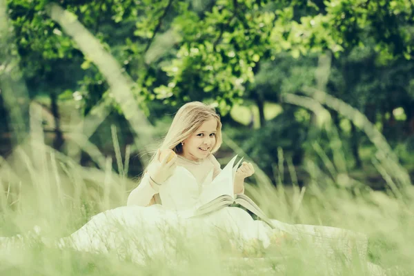 Liten flicka i klänning med fruktkorg och bok — Stockfoto