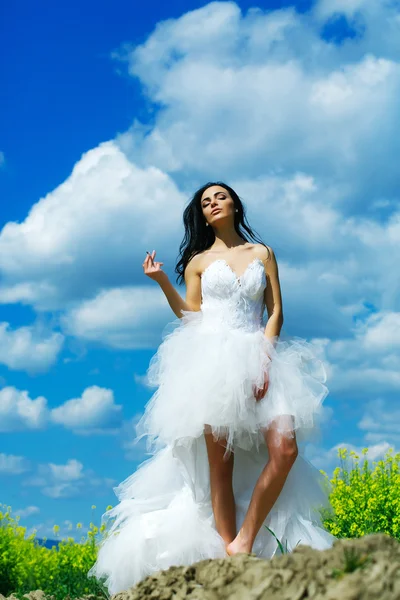 Pretty wedding girl on blue sky with cigarette — Stock Photo, Image