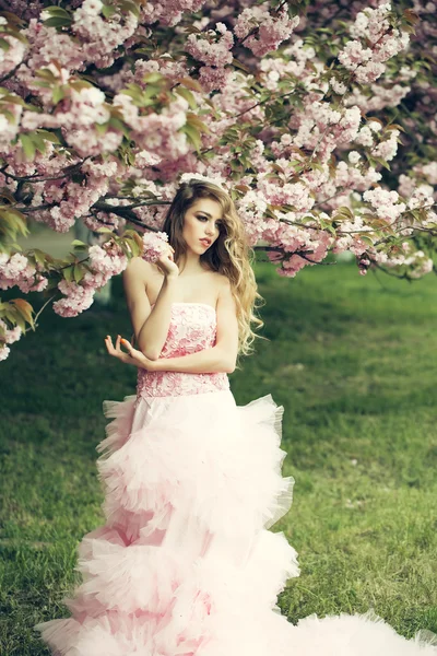 Vrouw in roze jurk in de buurt van bloom — Stockfoto