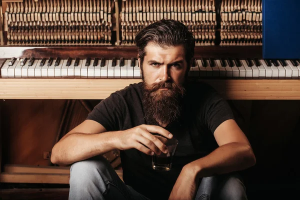 Homem barbudo com vidro perto de madeira piano — Fotografia de Stock