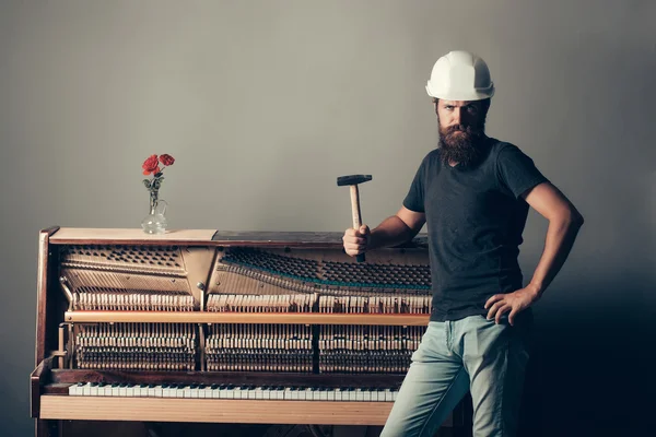 Man in de helm in de buurt van piano met hamer — Stockfoto