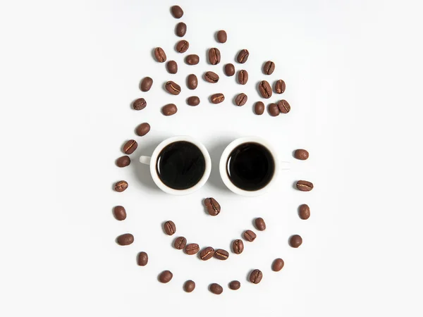 Souriant de grains de café dans des tasses isolées sur blanc — Photo