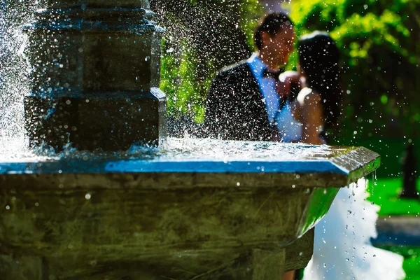 Bröllopsparet kyss nära fontänen vatten — Stockfoto
