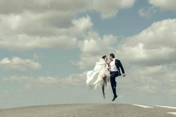 Casamento casal feliz correndo na estrada — Fotografia de Stock