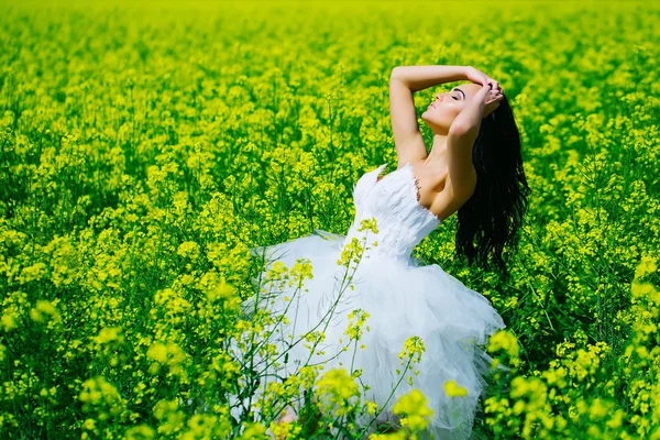 Ganska wedding flicka i gul gröna fältet blommor — Stockfoto