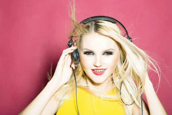 Mooie blonde dg meisje in hoofdtelefoon op roze — Stockfoto