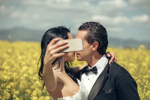 Boda pareja beso en campo amarillo flores — Foto de Stock