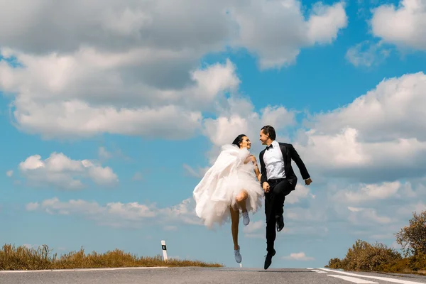 Boda feliz pareja corriendo en camino — Foto de Stock