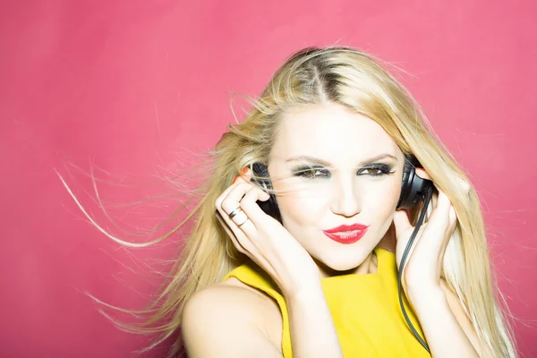 Vacker blond GD flicka i headsetet på pink — Stockfoto