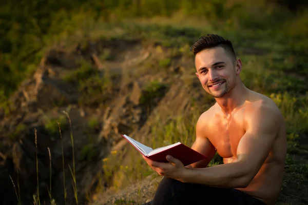 Smiling muscular man with book outdoor