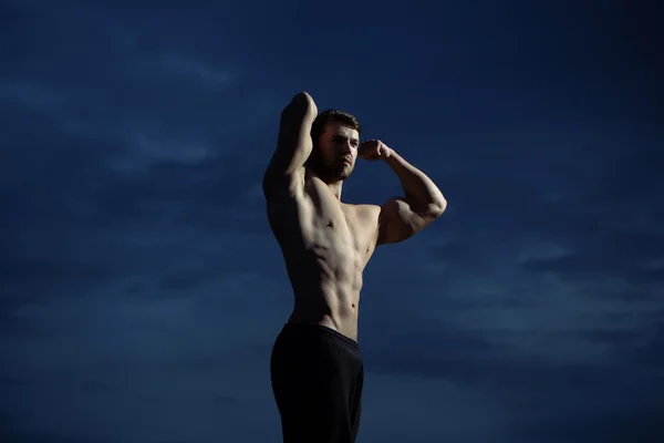 Sexy muscular macho man on blue sky — Stock Photo, Image