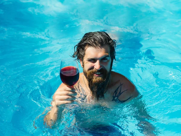 man with wine glass in swimming pool
