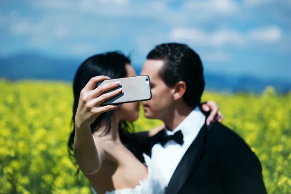 Matrimonio bacio coppia in campo fiori gialli — Foto Stock