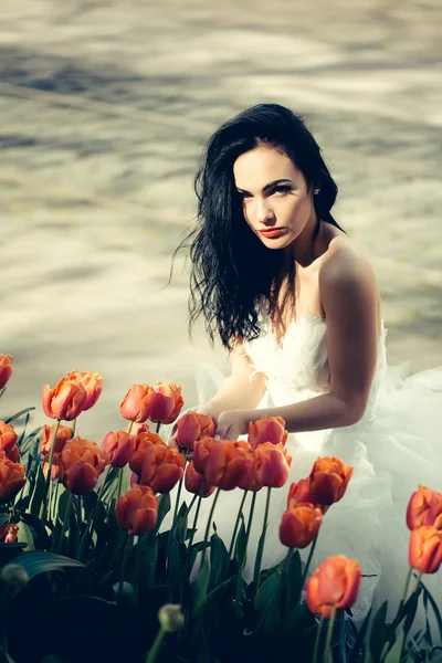 Bonita mulher de casamento perto de tulipas vermelhas — Fotografia de Stock