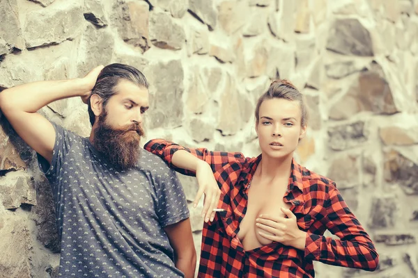 Couple smoking on stony wall background — Stock Photo, Image