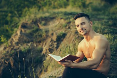 Kitap açık ile gülümseyen kaslı adam