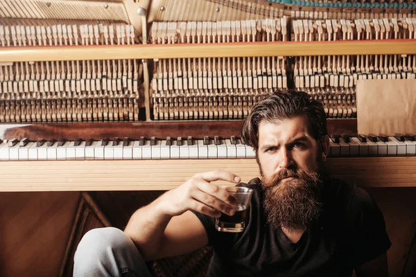 Homme barbu avec verre près du piano en bois — Photo