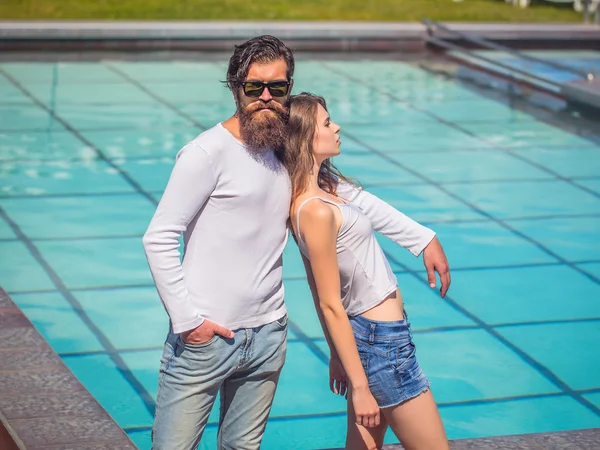 Pareja joven parada cerca de la piscina — Foto de Stock