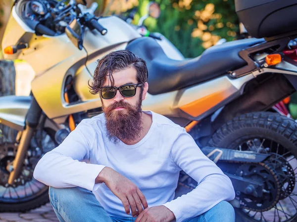 Homem atraente senta-se perto da motocicleta — Fotografia de Stock