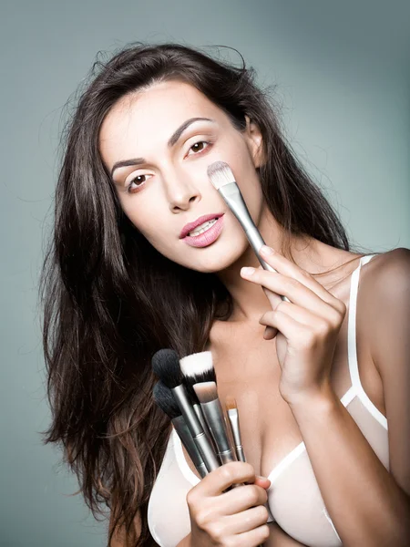 Mooie vrouw in beha met make-up borstel — Stockfoto