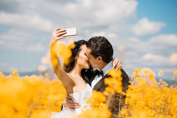 Bruidspaar kus in veld gele bloemen — Stockfoto