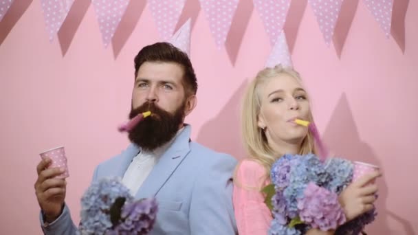 Celebration, friends, party, birthday concept. Couple wearing birthday hats and blowing favor horns. — Stock Video