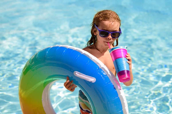 Летние дети Коктейль. Счастливый маленький мальчик с цветным надувным кольцом в открытом бассейне в жаркий летний день. Семейный отдых на пляже. — стоковое фото