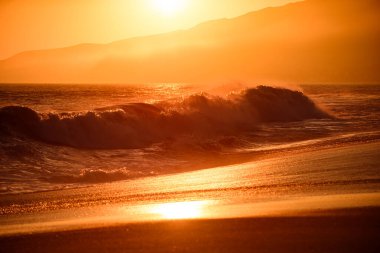 Deniz dalgaları kumsalında altın gün batımı. Gündoğumu manzarası.