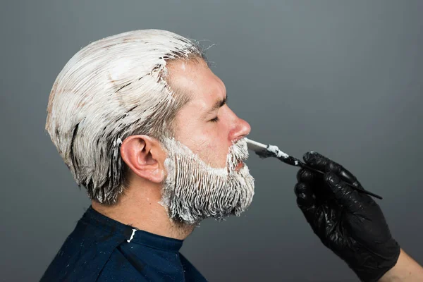 Волосатый бородатый мужчина. Окраска бороды. Парикмахер делает раскраску. — стоковое фото