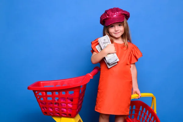 買い物中の女の子。販売。多くのドルのショッピングバッグを持つかわいい子供。ショッピングモールの近くのドレスシューズの娘の肖像画は楽しい. — ストック写真